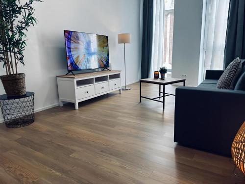 a living room with a flat screen tv on a white cabinet at Apartment ARTIC I Cityblick & Komfort in Nordhorn