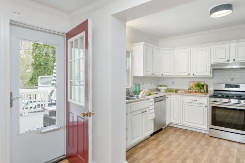 uma cozinha com armários brancos e uma porta vermelha em The Front Porch Vacation Rentals em Bristol