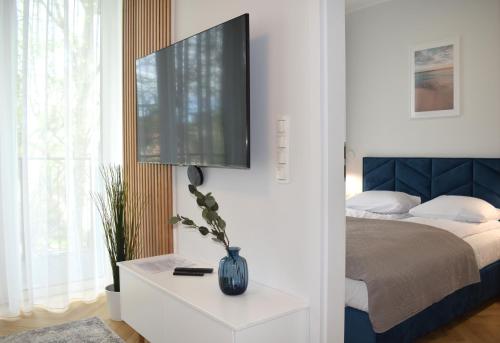 a bedroom with a bed and a tv on a wall at Apartos Seaside Garden Apartments I in Świnoujście