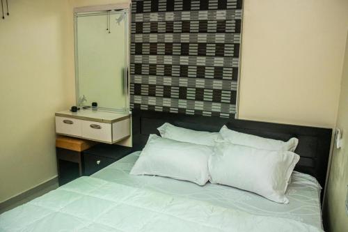 a bedroom with a bed with white pillows and a mirror at 2 bed room apartment in Port Harcourt