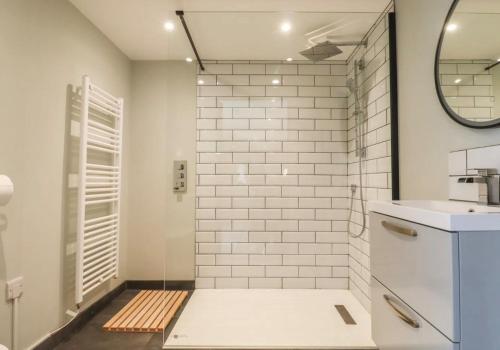 a bathroom with white subway tiles and a mirror at Artists Hideaway in Battle