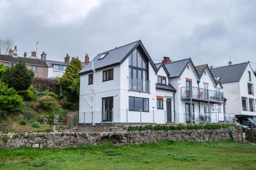 a large white house with a stone wall at Hiraethog in Menai Bridge