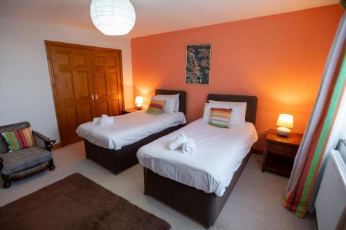 a room with two beds and a chair in it at Ty Bach, Llanbedrog in Pwllheli