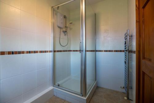 a shower with a glass door in a bathroom at Ty Bach, Llanbedrog in Pwllheli