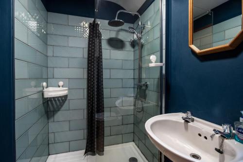 Un baño azul con lavabo y ducha. en Ty Bach, en Llanberis