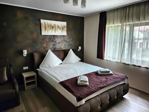 1 dormitorio con 1 cama con 2 toallas en Pensiunea Andrei Moieciu, en Moieciu de Jos