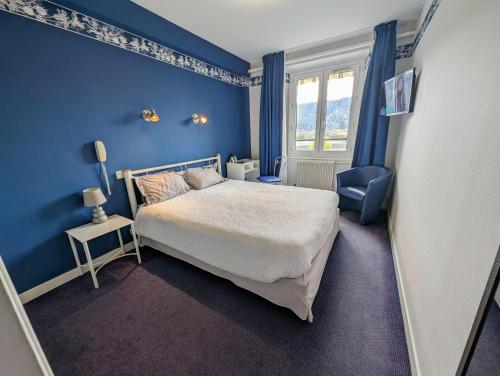 a blue bedroom with a bed and a chair at Logis Hôtel Le Beau Site in Chambon-sur-Lac