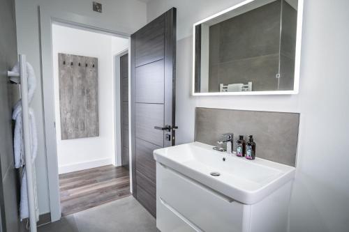 W łazience znajduje się biała umywalka i lustro. w obiekcie Cadnant Lodge w mieście Llangefni
