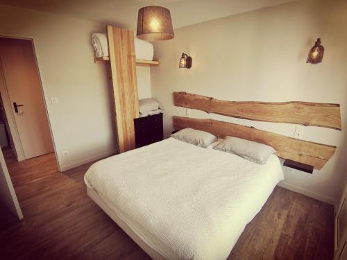 a bedroom with a white bed and a wooden headboard at Logis Hôtel Le Beau Site in Chambon-sur-Lac