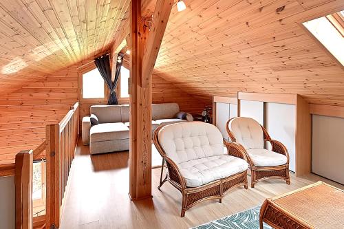 ein Wohnzimmer mit 2 Stühlen und einem Sofa in der Unterkunft Chalet Bois Cosy - Climatisé - Piscine privée in Ferdrupt