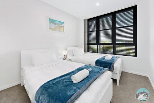 two beds in a white room with a window at Aircabin - Shell Cove - Waterview - 2 Bed Apt in Shellharbour