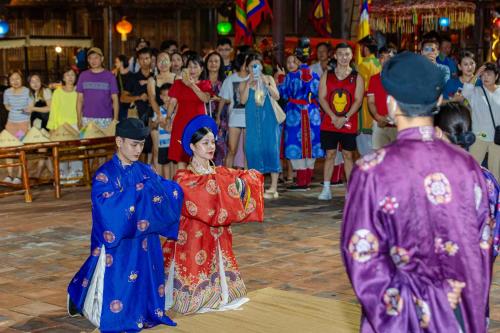 a group of people in traditional costumes walking in a crowd at Legacy Phú Quốc in Phu Quoc