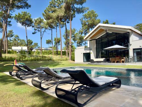 a group of lounge chairs next to a swimming pool at Belart Luxury Villa with Pool Golf and Beach in Aroeira