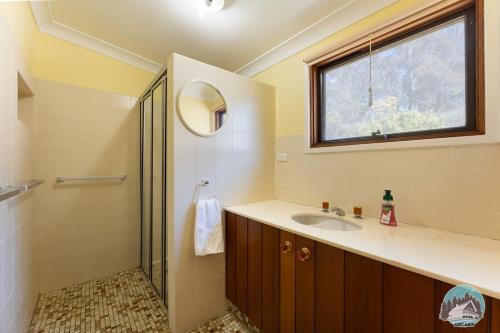 uma casa de banho com um lavatório e um chuveiro com uma janela em Aircabin - Oberon - Great Location - Comfy Chalet em Oberon
