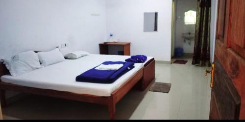 um quarto com uma cama com um cobertor azul em Mallick Palace em Neil Island