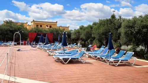 a row of lounge chairs with blue umbrellas at Studio with shared pool terrace and wifi at Sciacca in Sciacca
