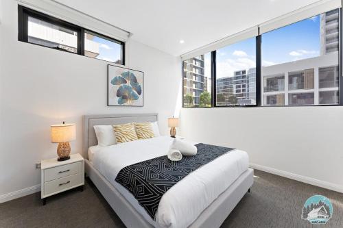 a bedroom with a bed and two large windows at Aircabin - Olympic Park - Cheerful - 3 Beds APT in Sydney
