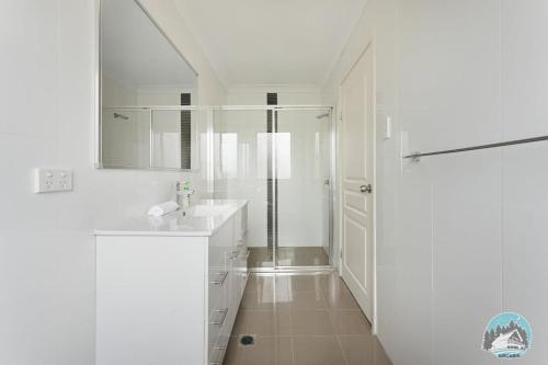 baño blanco con ducha y lavamanos en Aircabin - Telopea - Sydney - 5 Beds Holiday House en Sídney