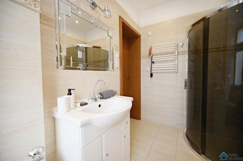 a white bathroom with a sink and a shower at Apartament Chopin in Sopot