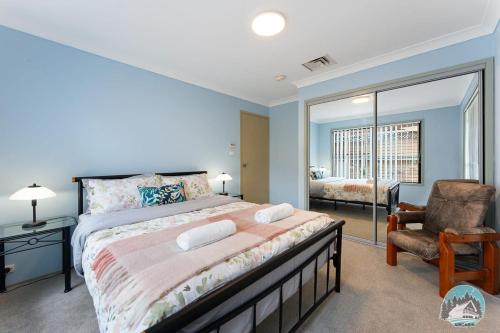 a bedroom with a large bed and a chair at Aircabin - Tuggerawong - Waterfront - 4 Beds House in Karraganbah