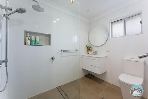 a white bathroom with a shower and a toilet at Aircabin - Tuggerawong - Waterfront - 4 Beds House in Karraganbah