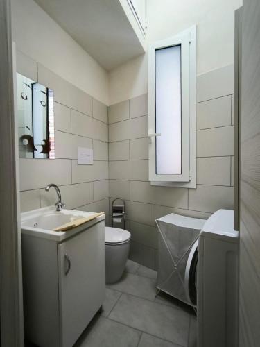 een badkamer met een wastafel, een toilet en een raam bij Da nonna Concetta in Donnalucata