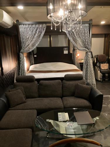 a bedroom with a bed and a couch and a glass table at X Hotel - Adult Only- in Sayama