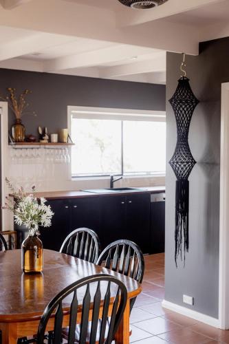 a kitchen with a table and chairs and a refrigerator at 'Lazy Susan's' Waterfront Shack in Primrose Sands
