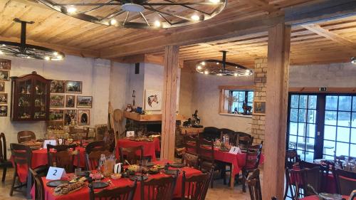 a dining room with red tables and chairs and a ceiling at Zirgu sēta "Klajumi" - Horse ranch "Klajumi" in Kaplava