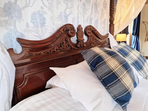 a bed with a wooden headboard and pillows at Lomond 5 with Private Hot Tub - Fife - Loch Leven - Lomond Hills - Pet Friendly in Kelty