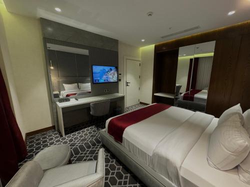 ein Hotelzimmer mit einem großen Bett und einem TV in der Unterkunft Ankawa Holiday Hotel in Erbil