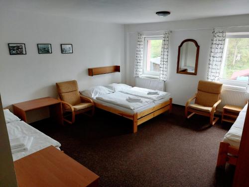 una camera con due letti e due sedie e uno specchio di Hotel Bartošovice a Bartošovice v Orlických Horách