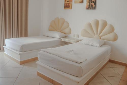 two beds in a room with white walls at Hotel Manzana Blanca 5th Avenue in Playa del Carmen