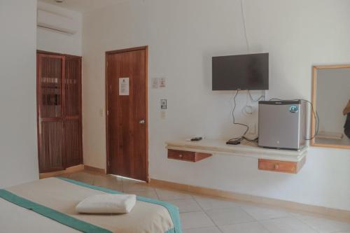 Habitación con cama y TV en la pared. en Hotel Manzana Blanca 5th Avenue en Playa del Carmen