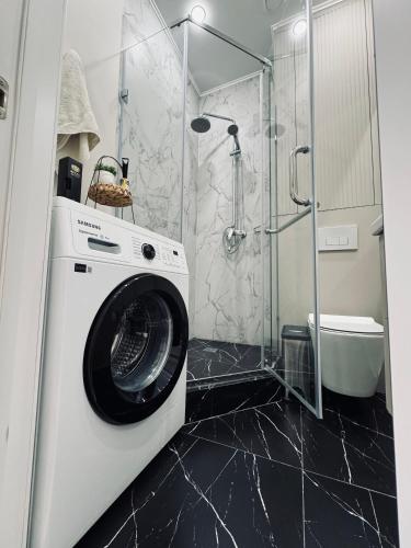 een wasmachine in een badkamer met een douche bij 2-х комнатные апартаменты в ЖК GreenLine.Asyl Mura in Taldykolʼ