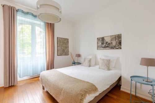 a white bedroom with a bed and a window at MAMRAY in Colmar