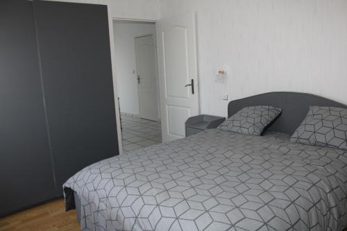 a bedroom with a bed with a gray and white comforter at Le gite de la Forêt in Herbsheim