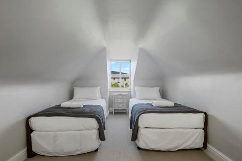 Duas camas num quarto branco com uma janela em Connage - Historic Battery Point Police Station em Hobart