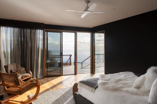- une chambre avec un lit, une chaise et un balcon dans l'établissement Siren Tasmania, à White Beach