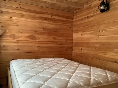 1 dormitorio con 1 cama en una pared de madera en Lakeside Tiny Cozy Retreat en Ulster