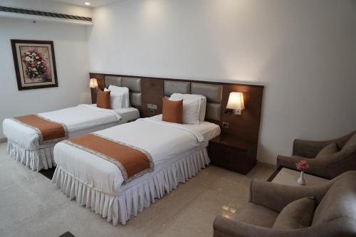 a hotel room with two beds and a couch at The Alcor Hotel in Jamshedpur