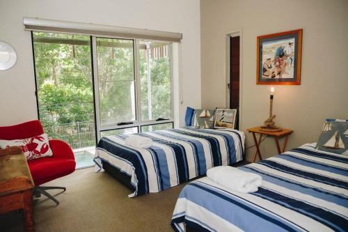 a room with two beds and a chair and a window at Family Beach House at Sebel Twin Waters Resort in Twin Waters