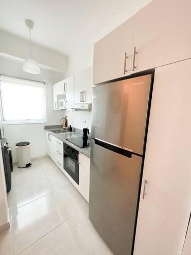 a kitchen with a stainless steel refrigerator and white cabinets at Juan Dolio Apartamento 204D 2Br Pool View in Juan Pedro