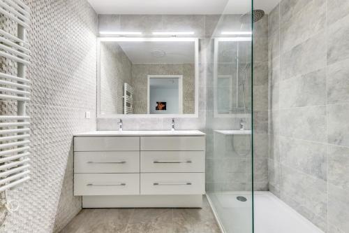 uma casa de banho branca com um lavatório e um chuveiro em Chic appartement en plein coeur de Levallois-Perret em Levallois-Perret