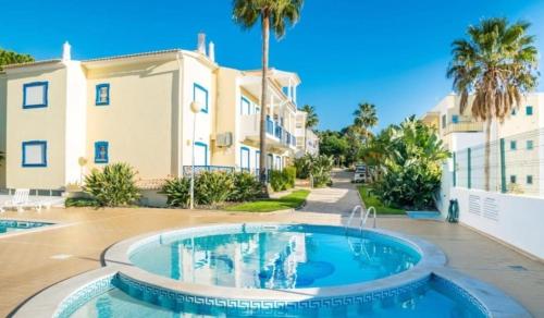 einem großen Pool vor einem Gebäude mit Palmen in der Unterkunft Flamingos Apartment with 2 swimming pool com check in e check out ao domingo em julho e agosto in Albufeira