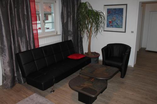 a living room with a black couch and a chair at Landhaus Goldenes Kreuz in Leutkirch im Allgäu