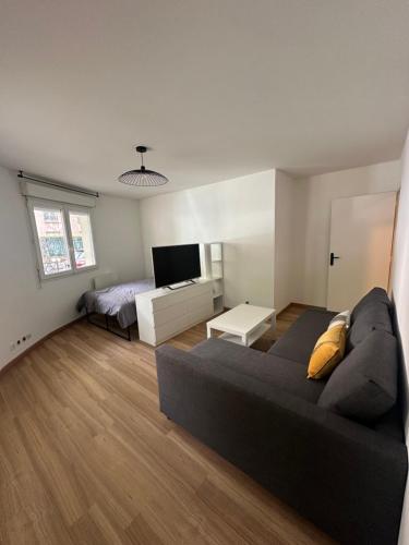 een woonkamer met een zwarte bank en een bed bij Appartement cosy, proche Paris in Rosny-sous-Bois