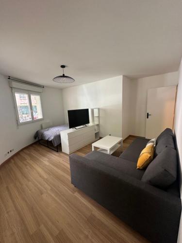 - un salon avec un canapé noir et un lit dans l'établissement Appartement cosy, proche Paris, à Rosny-sous-Bois