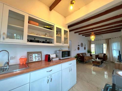 a kitchen with white cabinets and a living room at Akiba Guests Houses in Kribi