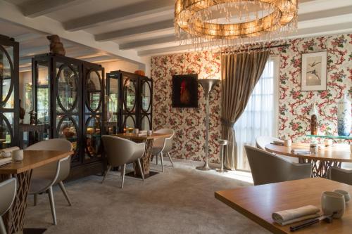 a restaurant with tables and chairs and a chandelier at La Mare aux Oiseaux, The Originals Collection in Saint-Joachim